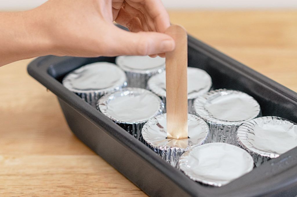 how to make planet-friendly ice lollies: the stick is poked through the foil in each cup