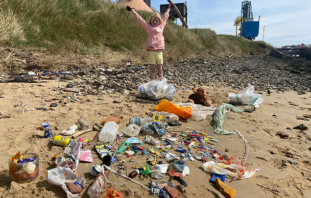 Rayer stands behind lots of plastic picked up on a beach clean