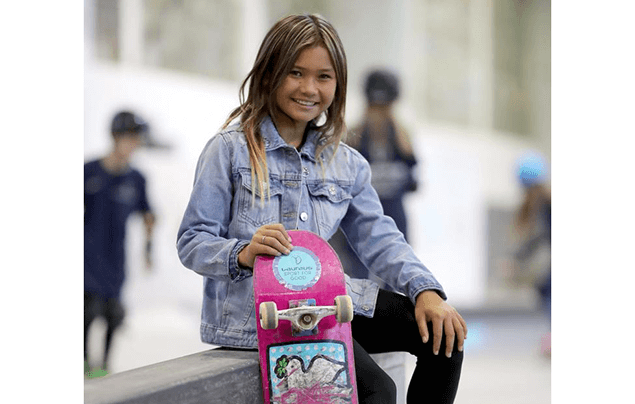 Sky Brown, a Japanese-British skateboarder, sits with her pink board beside a skate park