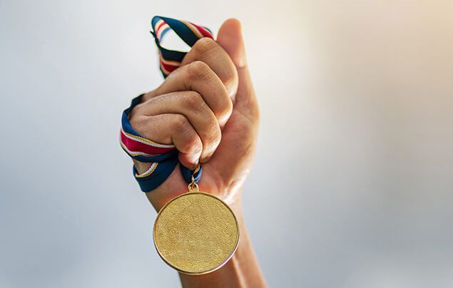 Facts about the olympics | a hand holds a gold medal