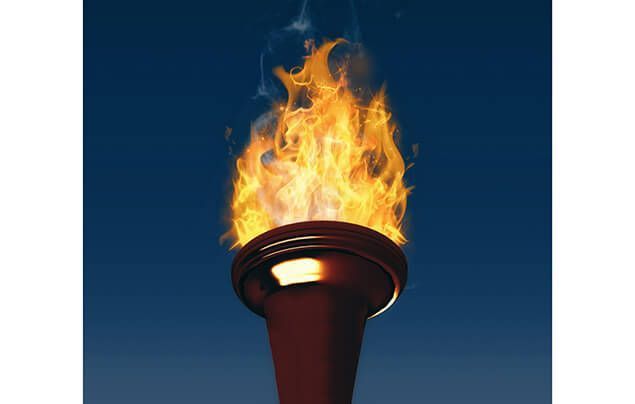 facts about the olympics | a torch burns against the night sky