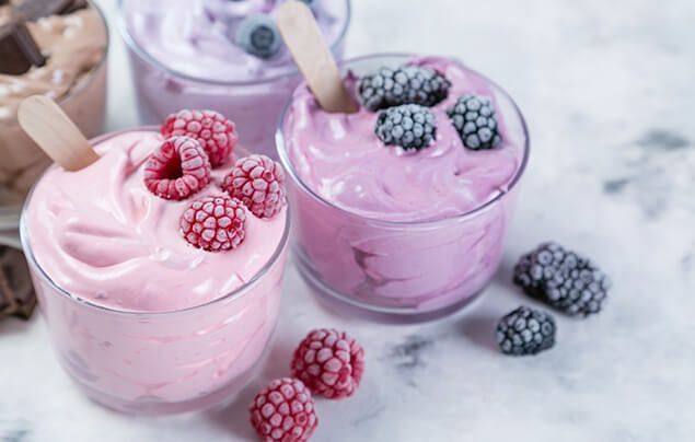 delicious pink homemade ice cream in a glass bowl, with a few frozen berries scattered on top