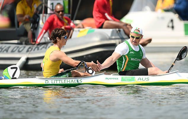 paralympic athlete dylan sits in his canoe on a lake. he slaps palms with a teammate and looks pleased.