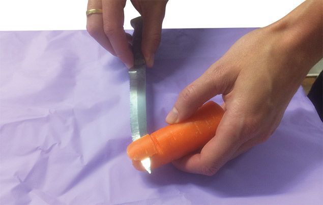 halloween recipe | an adults uses a knife to carefully cut a slice into a carrot | halloween recipe
