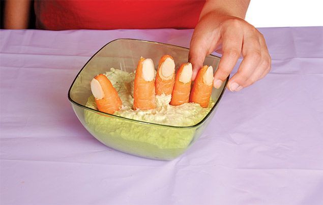 halloween recipe | a group of carrot 'fingers' sit in a bowl of green guacamole