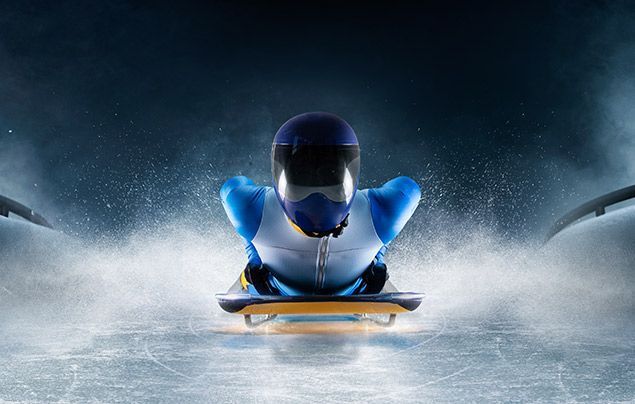 winter olympics facts | a skeleton bobsleigh rider lies on a narrow board and slides across the ice