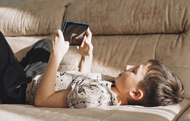Screen time for kids: child laying on the sofa using a tablet