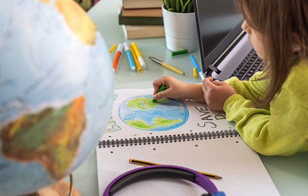 eco-anxiety | a young girl sits at a desk. she is making a poster, drawing the Earth and writing 'save the planet' beneath it.