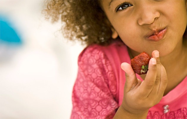 brain food | a young Black girl eats a strawberry
