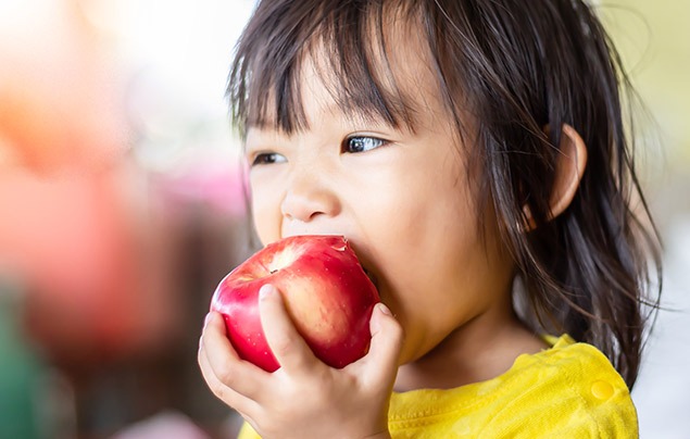 a young girl bites into an apple