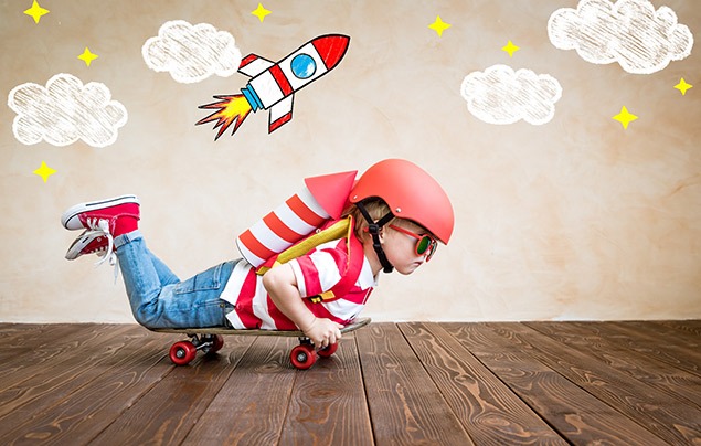 a young boy lying on a skateboard pretends to be on a rocketship
