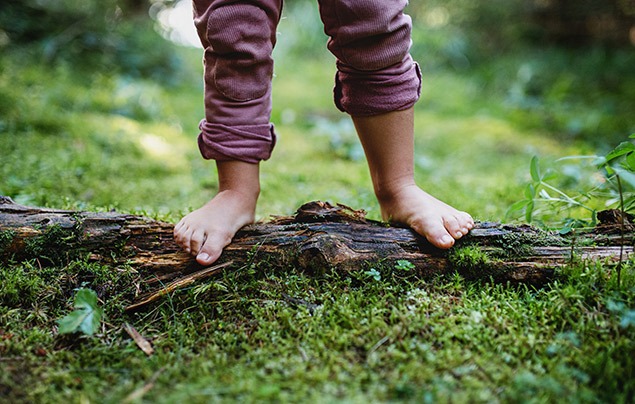 child standing on a log with bare feet