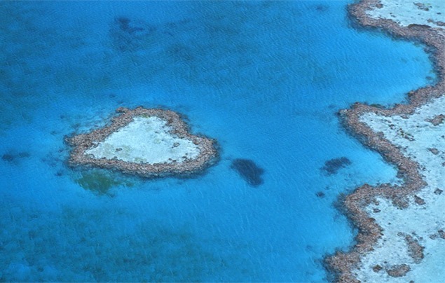 a small island just off the coast shaped like a heart, surrounded by blue sea