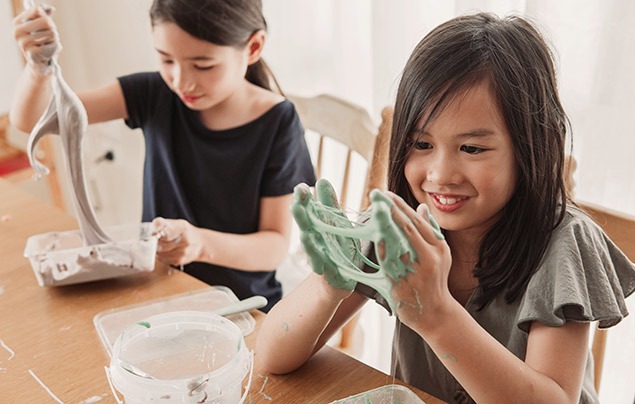 sensory play | two young girls sit at a table making green slime