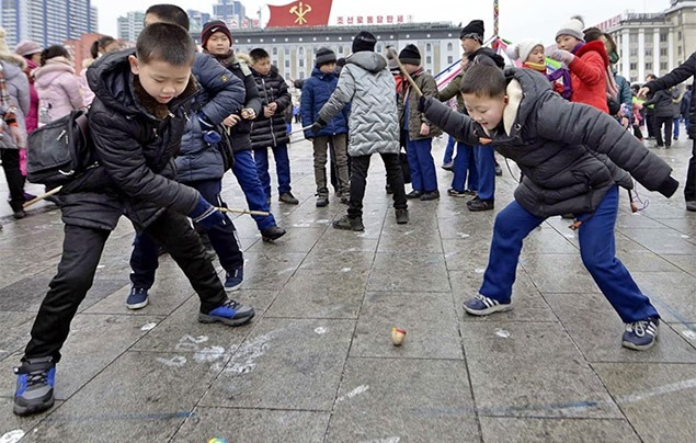 winter games for kids | children play with spinning tops on a hard tiled floor outside