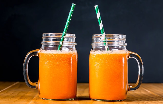 april fools' pranks | two glasses of orange juice standing next to eachother with green paper straws in