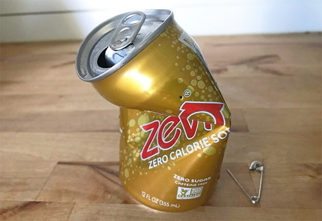 science experiments for kids | an open gold can of pop, crushed in the middle, with a safety pin beside it