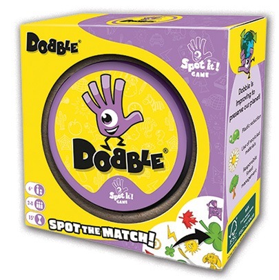 The image shows a box of the game “Dobble” (also known as “Spot It!”), similar to Bananagrams in its quick play style. The purple and yellow box features a cartoon hand logo, “Spot the Match!” text, for ages 6+, 2-8 players, 15 minutes.