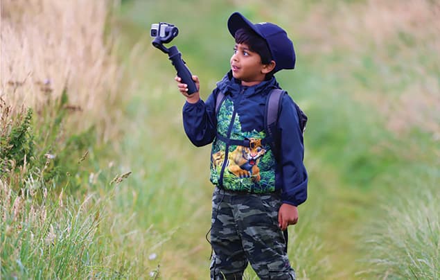 A young boy, Aneeshwar Kunchala, holds a camera on a stick to film himself
