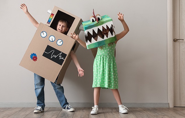 a decorative image of two children wearing homemade costumes - one is a crocodile and one a robot, both made from cardboard boxes